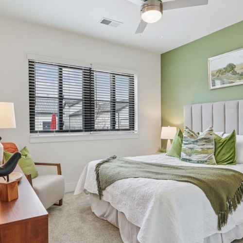  A bedroom with a large bed, a wooden side table, and a ceiling fan.