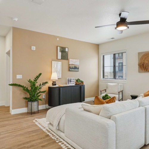 Living room with white couch and ceiling fan at Solace at the Ranch apartments for rent in Colorado Springs.